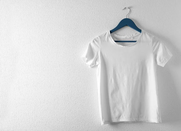 Kleiderbügel mit weißem T-Shirt auf hellem Hintergrund. Design-Attrappe — Stockfoto