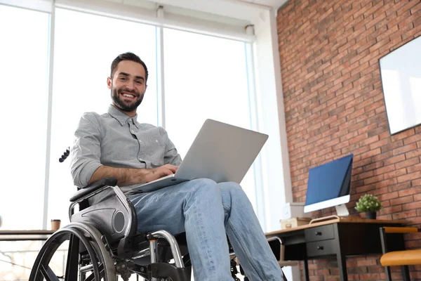 Porträt eines jungen Mannes im Rollstuhl mit Laptop im Büro — Stockfoto