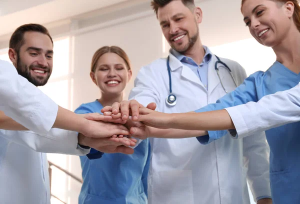 Team of medical doctors putting hands together indoors. Unity concept — Stock Photo, Image