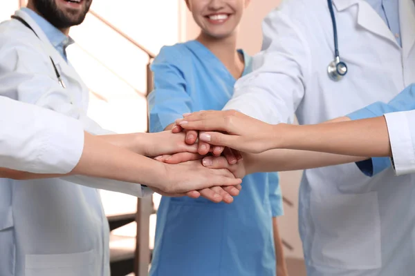 Equipo de médicos poniendo las manos juntas en el interior, primer plano. Concepto de unidad —  Fotos de Stock