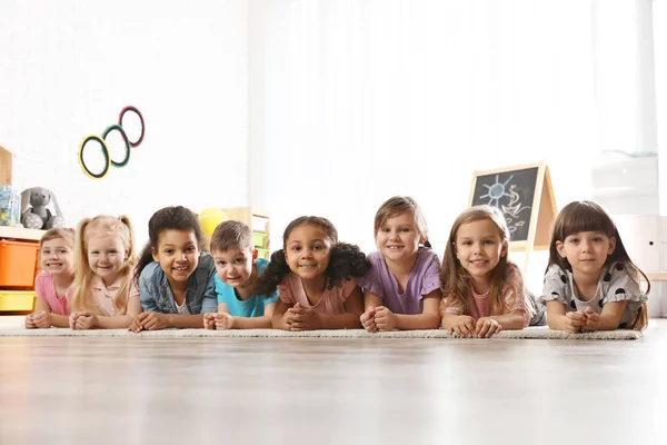 Groupe de petits enfants mignons couchés sur le sol à l'intérieur. Activités de jeux pour la maternelle — Photo