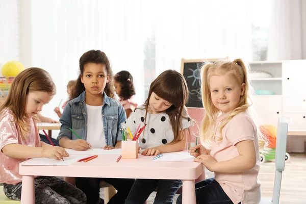 Entzückende Kinder, die sich an einem Tisch im Haus versammeln. Spielerische Aktivitäten im Kindergarten — Stockfoto