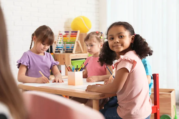 Schattige kinderen tekenen samen aan tafel binnenshuis. Kleuterschool speeltijd activiteiten — Stockfoto