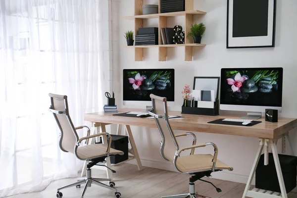 Moderno lugar de trabajo con escritorio grande y computadoras en la habitación. Interior con estilo —  Fotos de Stock