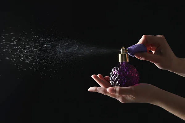 Mulher segurando garrafa de perfume de luxo em fundo preto, close-up. Espaço para texto — Fotografia de Stock
