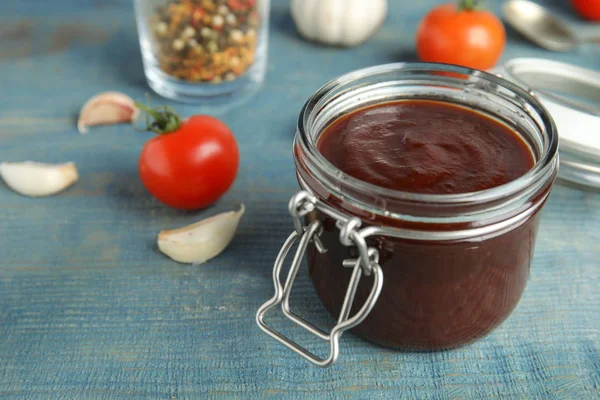 Glas mit leckerer Barbecue-Sauce auf blauem Holztisch. Raum für Text — Stockfoto