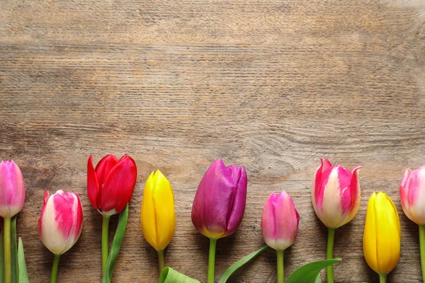 Hermosos tulipanes y espacio para texto sobre fondo de madera, vista superior. Flores de primavera — Foto de Stock