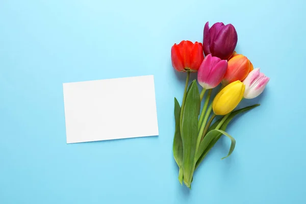 Csokor gyönyörű tavaszi virágok és üres kártyát a színes háttér, lapos feküdt. Szóköz a szöveghez — Stock Fotó