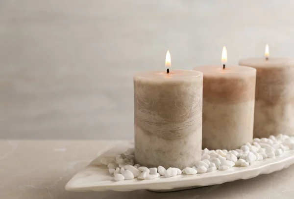 White plate with three burning candles and rocks on table. Space for text — 스톡 사진