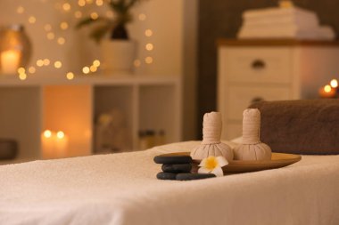 Spa salonunda masaj masasında bitkisel kompres ve taşlar. Metin için alan