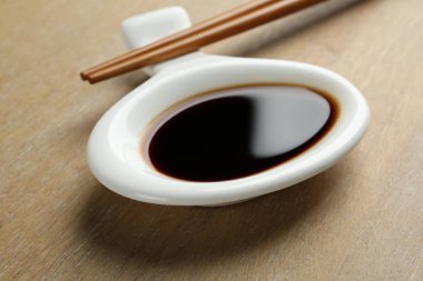 Ahşap arka plan üzerinde çubukları ile soya sosu Çanak, closeup