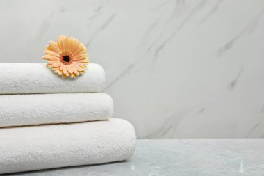 Açık arka plan karşı gri masa üzerinde çiçek ile taze havlu Yığını. Metin için alan