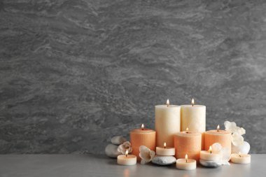 Gri arka plan karşı masada mumlar, çiçekler ve taşlar ile güzel kompozisyon. Metin için alan