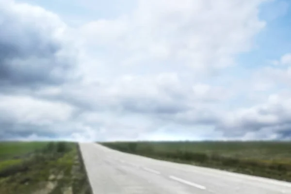 Blurred view of blue cloudy sky and asphalt road — Stock Photo, Image