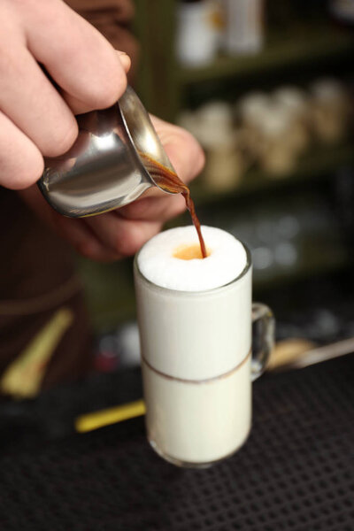 Бариста добавляет кофе в молоко на стойке, вид крупным планом
