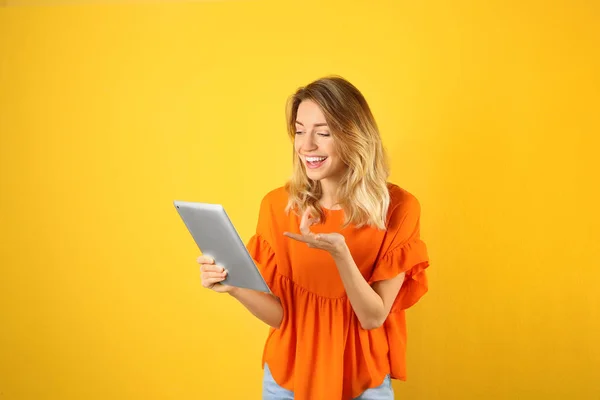 Mulher usando tablet para bate-papo por vídeo em fundo de cor — Fotografia de Stock