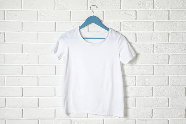 Hanger met wit t-shirt tegen bakstenen muur. Mockup voorontwerp — Stockfoto