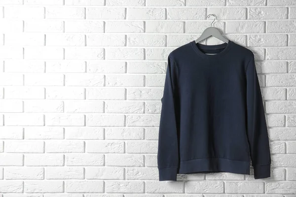 Hanger met donker Sweatshirt tegen bakstenen muur. Mockup voorontwerp — Stockfoto