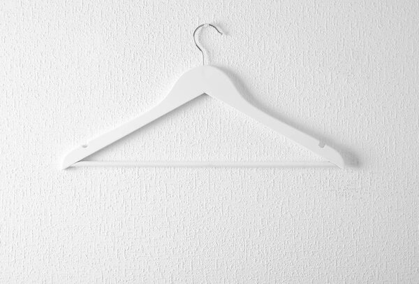 Пустая вешалка для одежды на светлой стене. Шкаф для одежды
