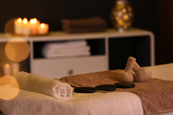 Herbal compresses and stones on massage table in spa salon