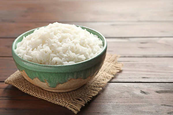 Tigela de arroz branco cozido saboroso na mesa de madeira. Espaço para texto — Fotografia de Stock