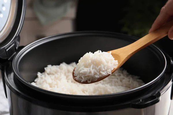 Женщина берет вкусный рис с ложкой из плиты на кухне, крупным планом — стоковое фото