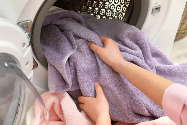 Vrouw die handdoeken uit de wasmachine haalt in de wasruimte — Stockfoto