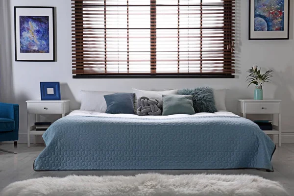 Современный интерьер с удобной двуспальной кроватью и окнами жалюзи — стоковое фото