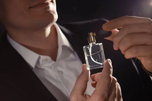 Przystojny mężczyzna stosowania perfum na szyi na czarnym tle, zbliżenie — Zdjęcie stockowe