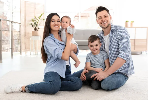 Счастливая пара с детьми, сидящими на полу дома. Семейные выходные — стоковое фото