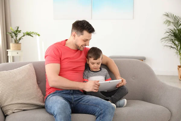Хлопчик і його батько з планшетом, сидячи на дивані вдома. Сімейного часу — стокове фото