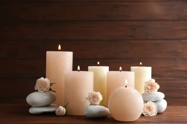 Σύνθεση από φλεγόμενα κεριά, πέτρες σπα και λουλούδια στο τραπέζι. Χώρος για κείμενο — Φωτογραφία Αρχείου