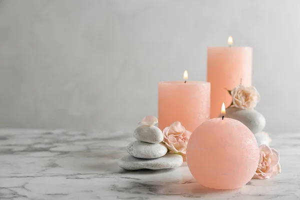 Burning candles, spa stones and flowers on table. Space for text