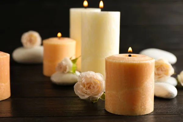 Burning candles, spa stones and flowers on table. Space for text