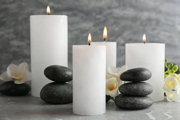Горящие свечи, спа-камни и цветы на столе — стоковое фото