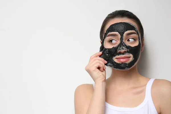 Beautiful young woman removing black mask from her face on white background. Space for text — Stock Photo, Image