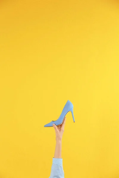 Женщина держит классическую туфлю на высоком каблуке на жёлтом фоне, крупным планом. Пространство для текста — стоковое фото