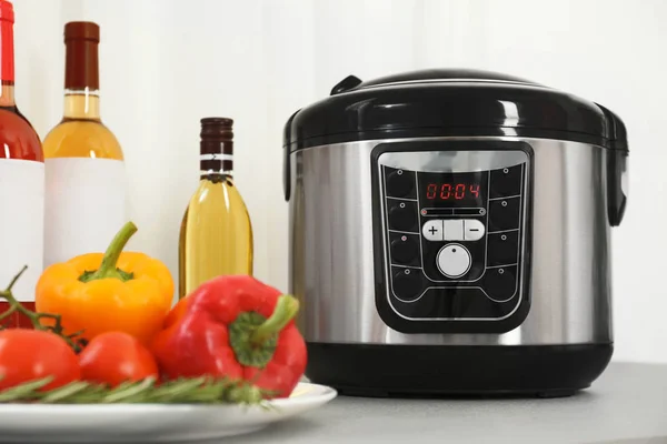 Modern multi cooker and products on kitchen table — Stock Photo, Image