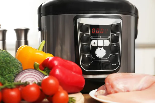 Modern multi cooker and ingredients on wooden table — Stock Photo, Image