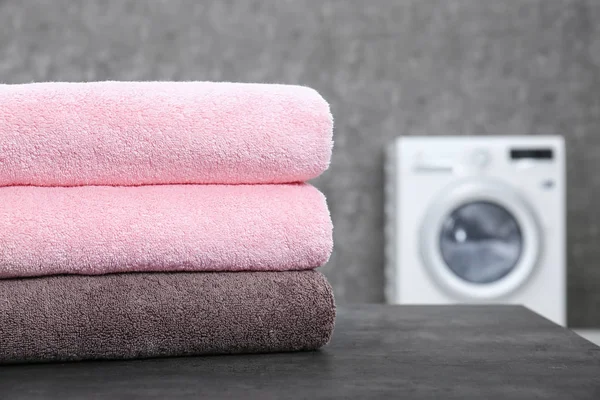 Pila di asciugamani puliti sul tavolo in lavanderia, primo piano. Spazio per testo — Foto Stock