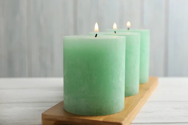 Placa de bambú con tres velas encendidas en la mesa —  Fotos de Stock