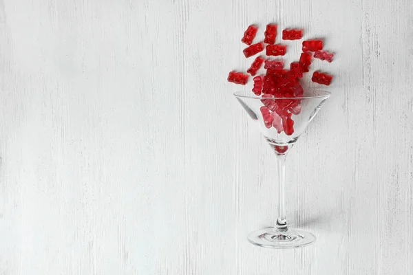 Bicchiere Martini con deliziosi orsi gelatina su sfondo in legno, vista dall'alto. Spazio per testo — Foto Stock