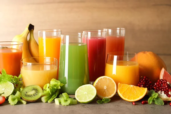 Vasos con diferentes jugos y frutas frescas en la mesa — Foto de Stock