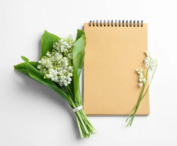 Notebook and lily of the valley bouquet on white background, flat lay. Space for text — Stock Photo, Image