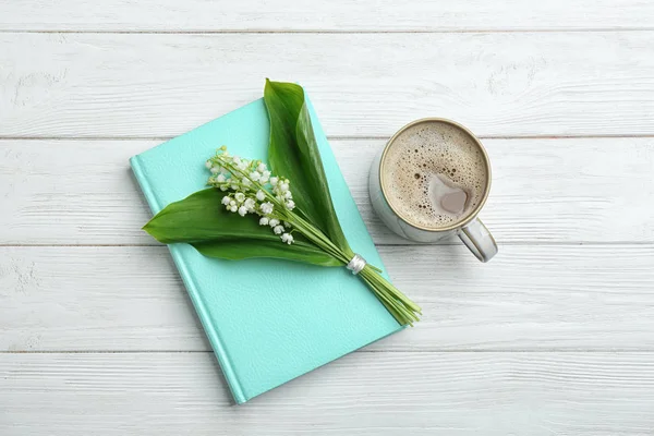 Platte lay samenstelling met notebook, Lily of the Valley boeket en koffie op witte houten achtergrond — Stockfoto