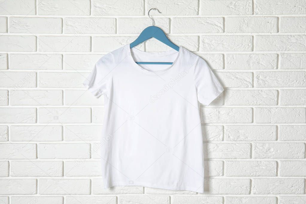Hanger with white t-shirt against brick wall. Mockup for design