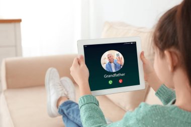 Evde görüntülü sohbet yoluyla dedesi ile sohbet için tablet kullanarak küçük kız Closeup görünümü