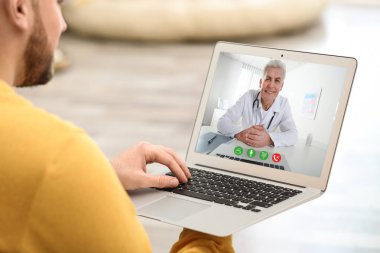 Adam evde görüntülü sohbet yoluyla doktor ile online danışma için dizüstü bilgisayar kullanarak, closeup