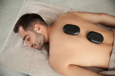 Yakışıklı adam spa salonunda sıcak taş masajı alan, üst görünümü