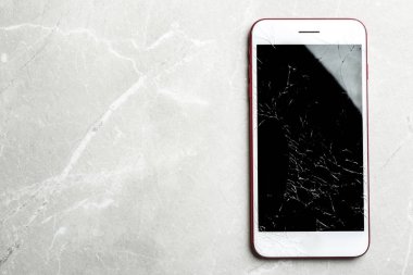 Kırık ekrana ve masadaki metin alanıyla modern akıllı telefon, üst görünüm. Cihaz onarımı